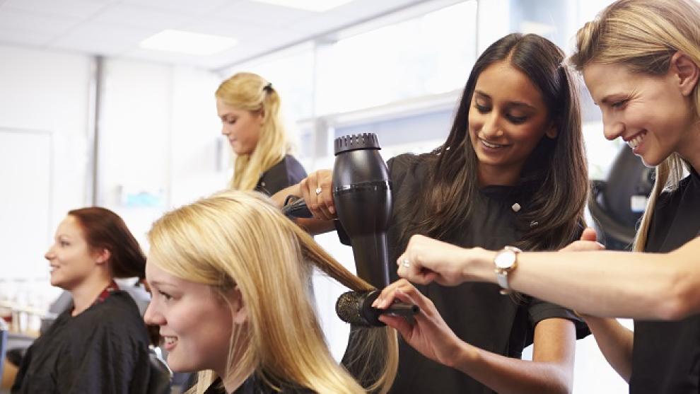 Apprentice hairdresser learning on the job