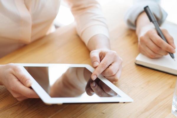 People using an iPad and writing notes